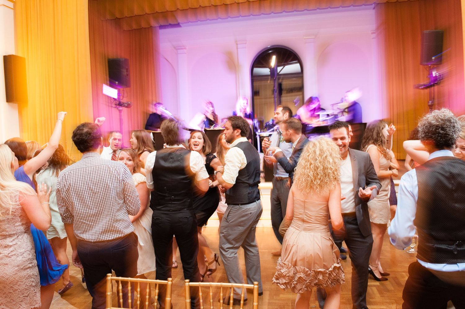 Wedding guests dancing energetically on crowded reception dance floor with live band performing.
