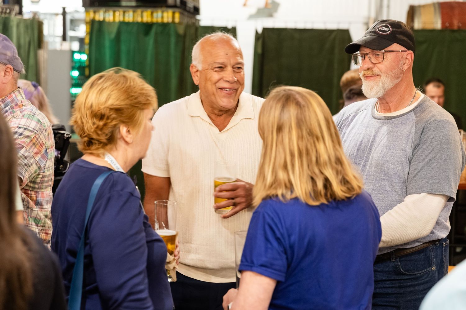 A diverse group of people socializing and laughing at an indoor gathering event.