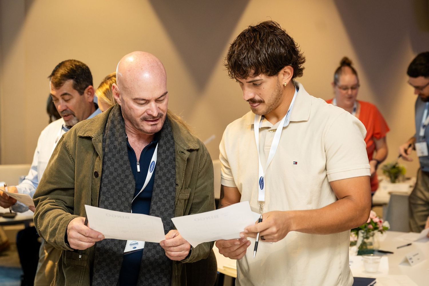 Two men reviewing documents together at a professional conference event indoors.
