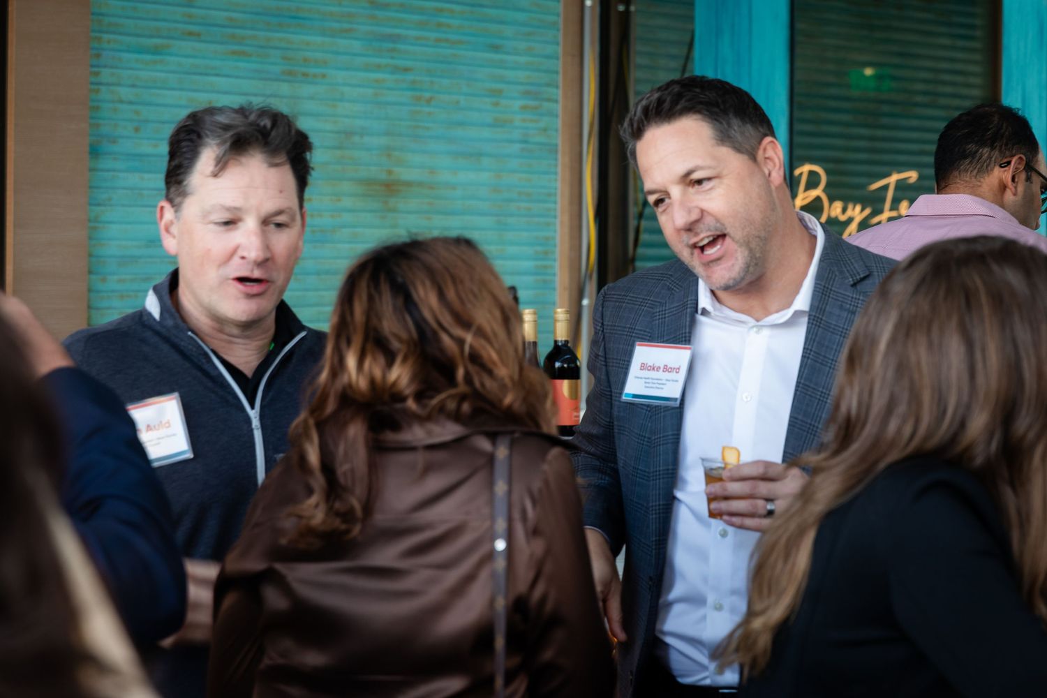 Two men wearing name badges smiling and talking at an Orlando Health Bay Inn networking reception.