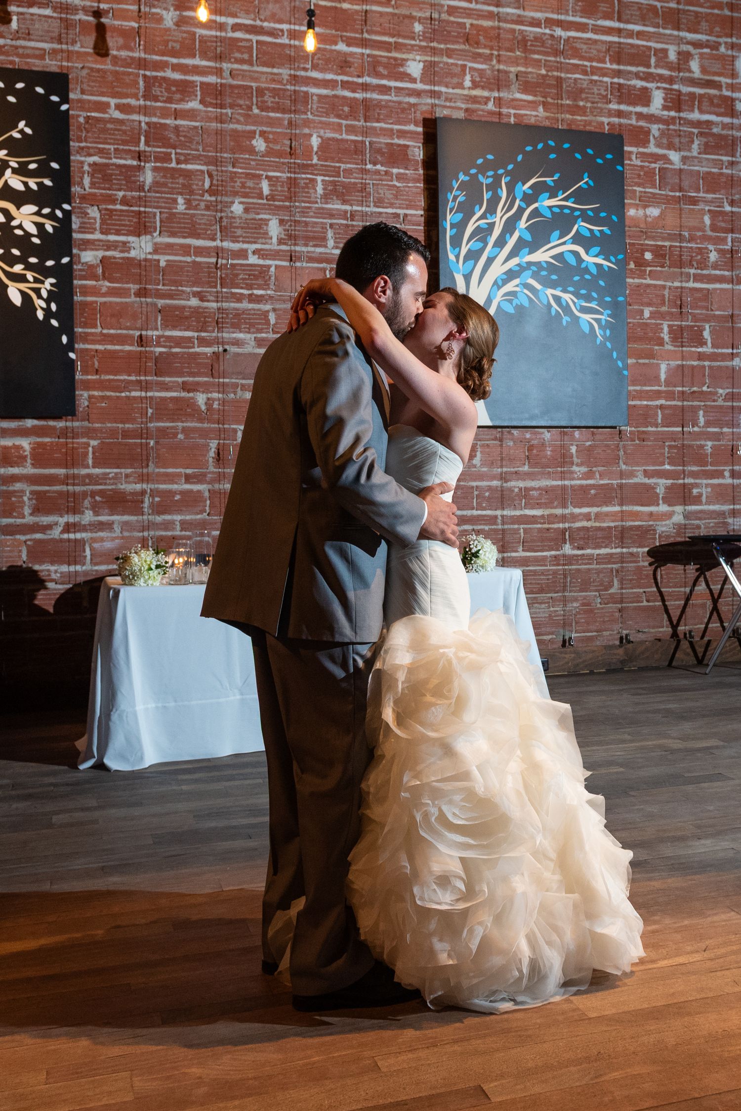Bride and groom share romantic first dance in rustic brick venue.