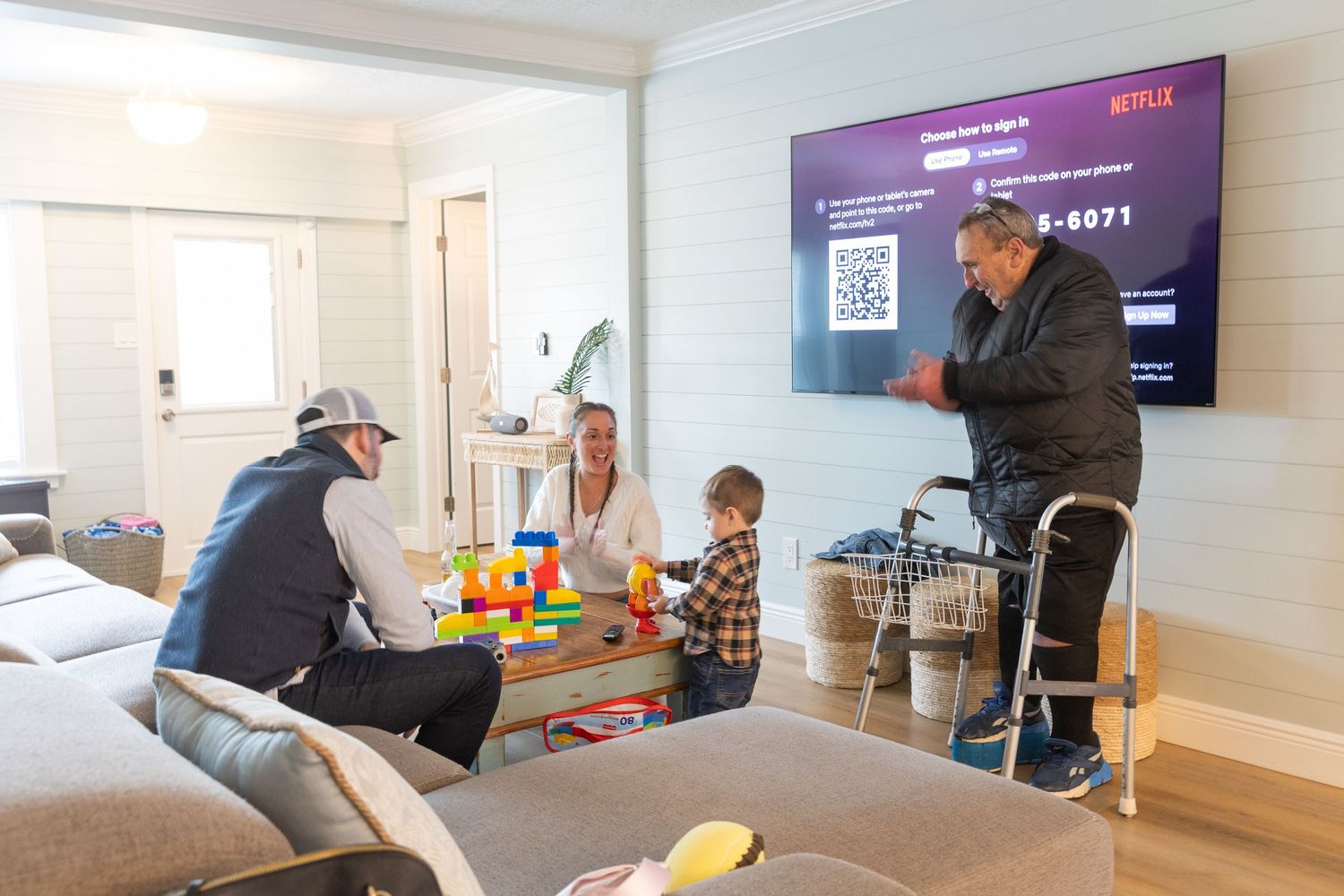 Family gathering in a cozy living room with a Netflix screen displayed on a large wall-mounted TV.