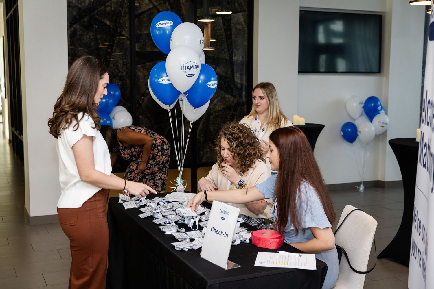 Women at a registration table with blue and white balloons at a corporate Samsung event.