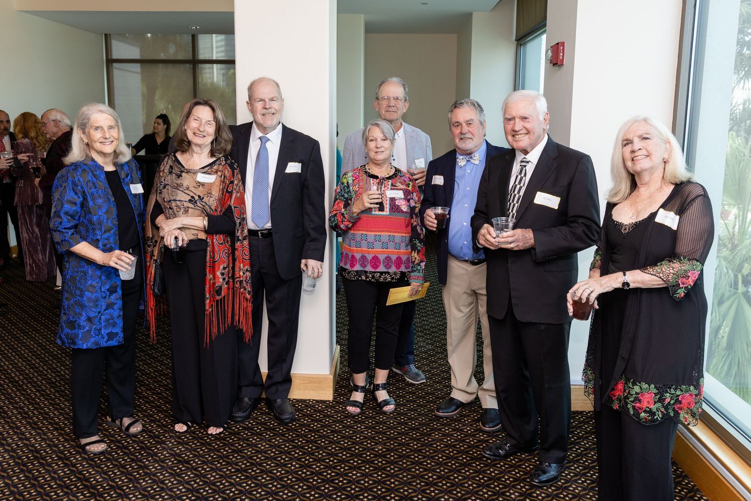 Group of eight adults posing together at a formal awards reception event in a modern venue.
