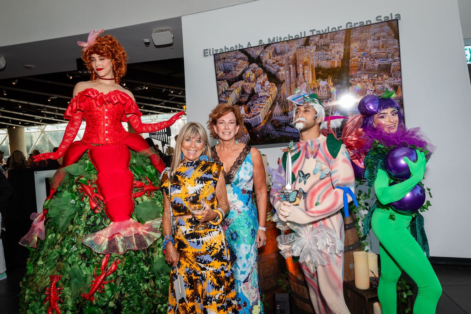 Group of people in colorful costumes and formal wear posing together at a festive event.