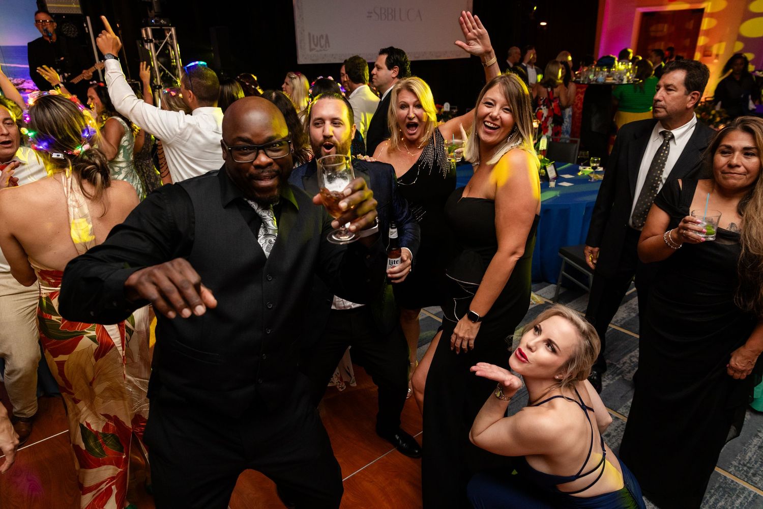 Guests dancing and celebrating at a lively formal gala event with colorful decorations.