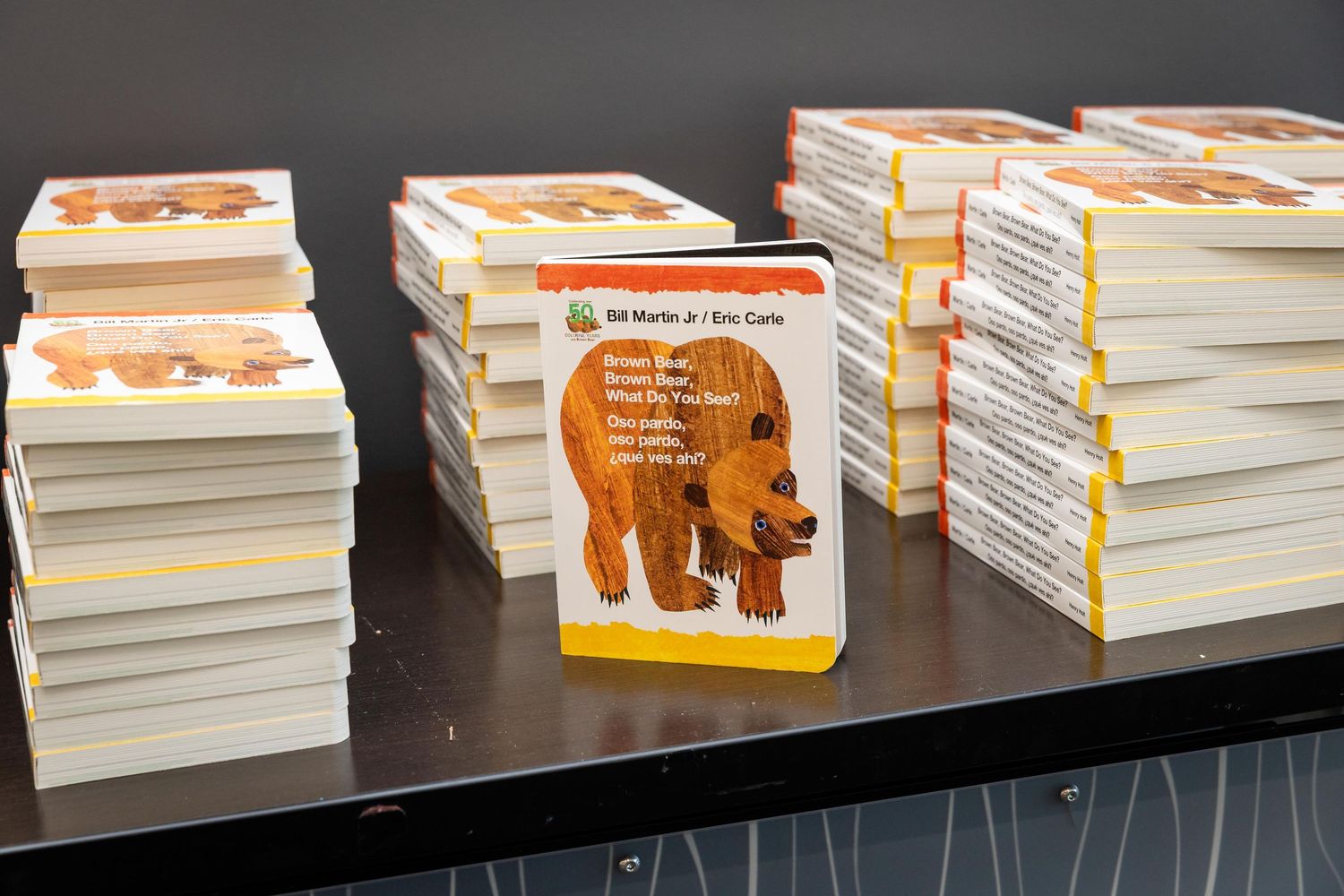 Stacks of Brown Bear, Brown Bear, What Do You See? books by Bill Martin Jr. and Eric Carle displayed on a shelf.