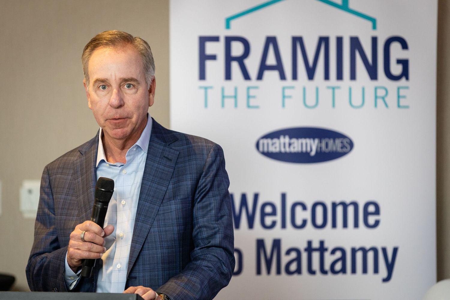 Executive speaks at Mattamy Homes Framing the Future event, standing at podium with branded banner backdrop.