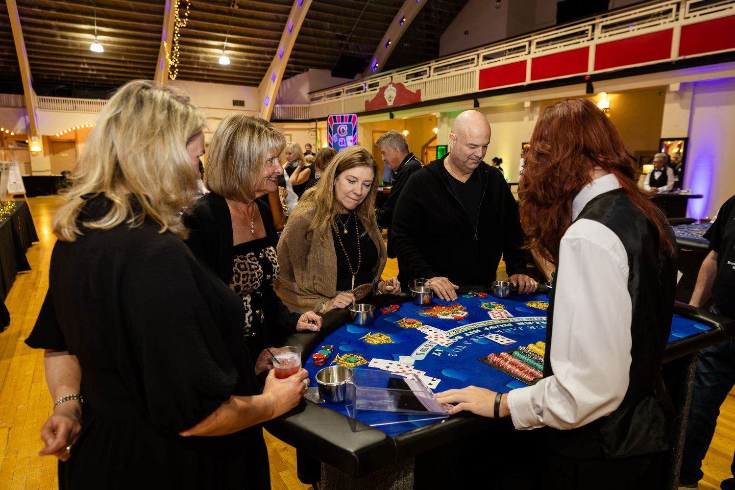Guests enjoy a casino night event at a roulette table with a dealer in a formal venue.