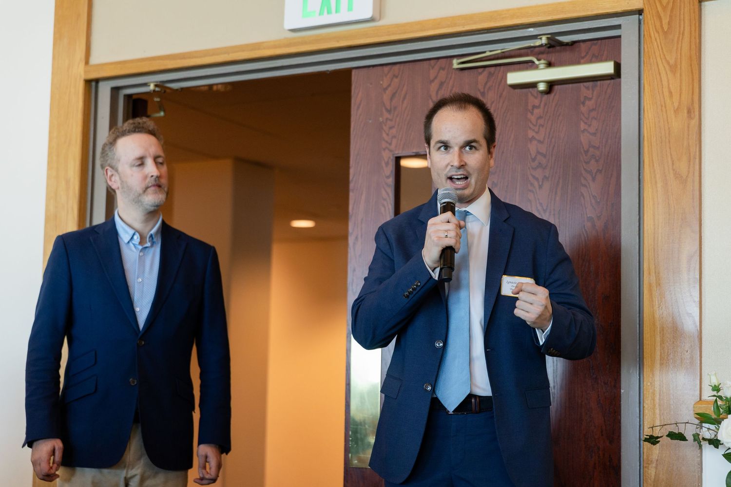 Two men in navy blazers, one speaking into microphone, presenting at The Florida Orchestra awards event.