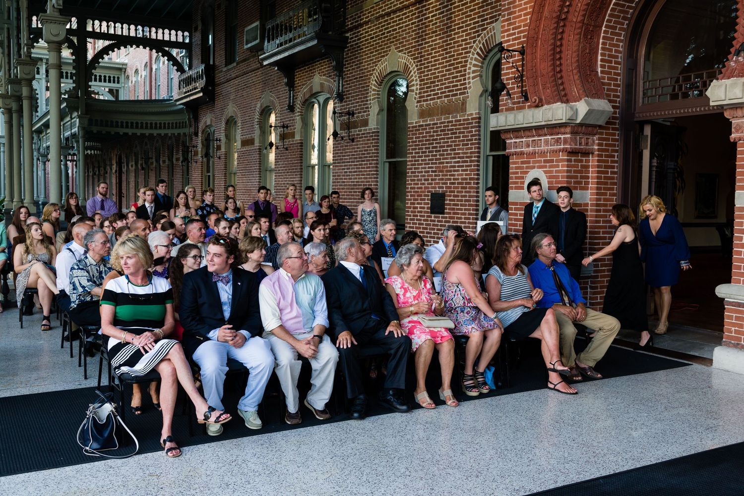 Guests seated in rows at an elegant brick venue during a formal ceremony or event.
