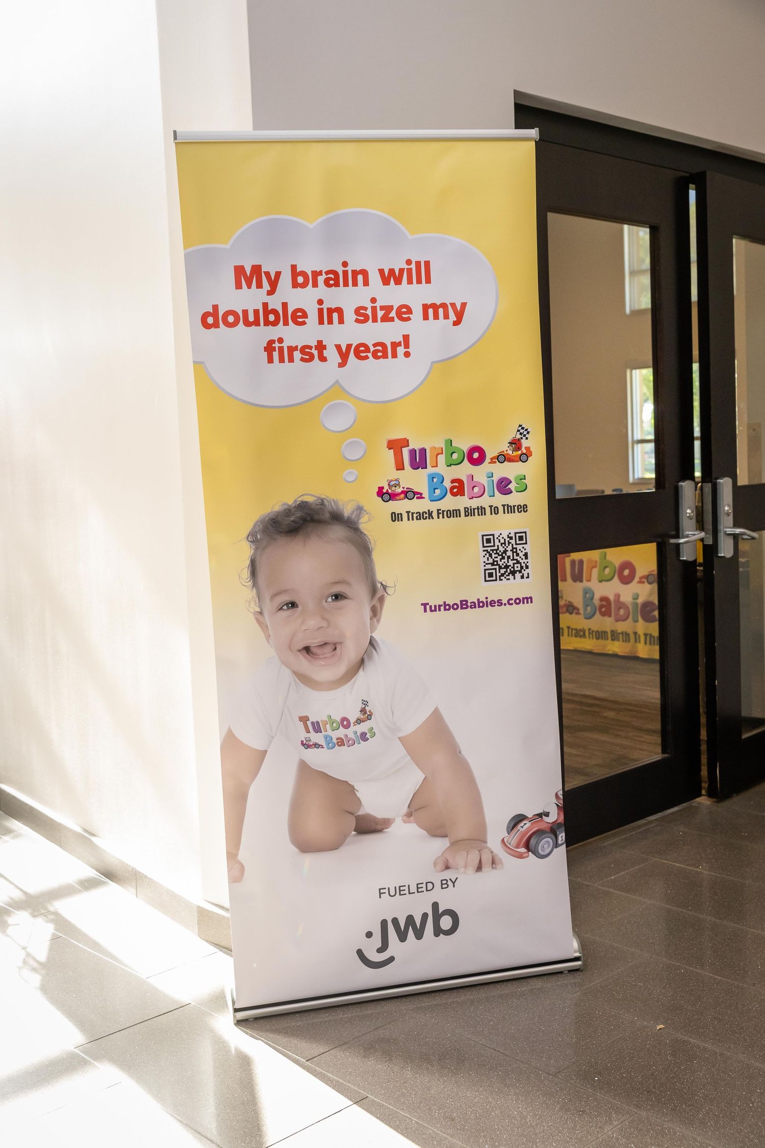 Turbo Babies program banner fueled by JWB, featuring a smiling baby with brain development facts.