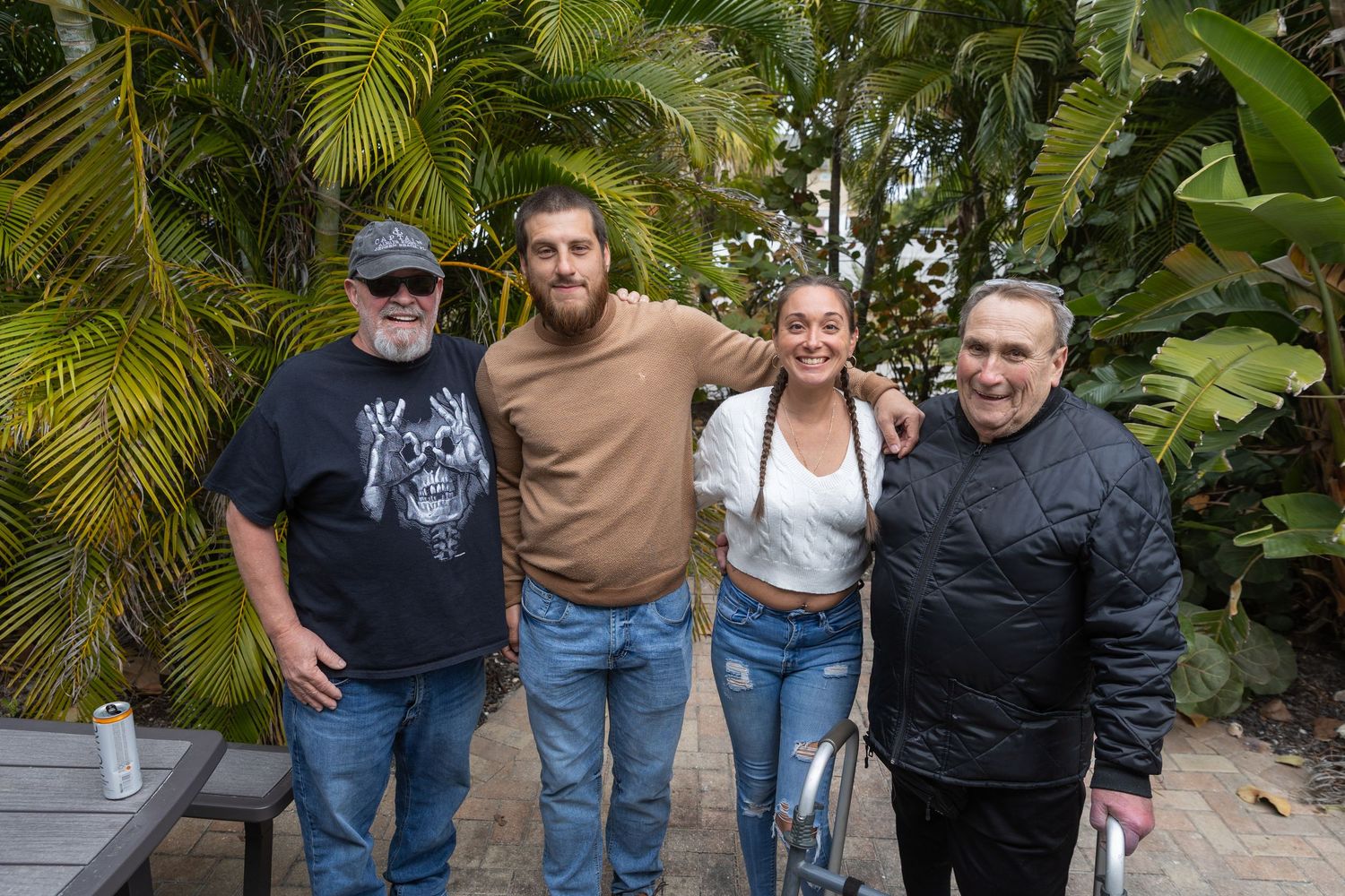 Four people posing together outdoors in a lush tropical garden setting.