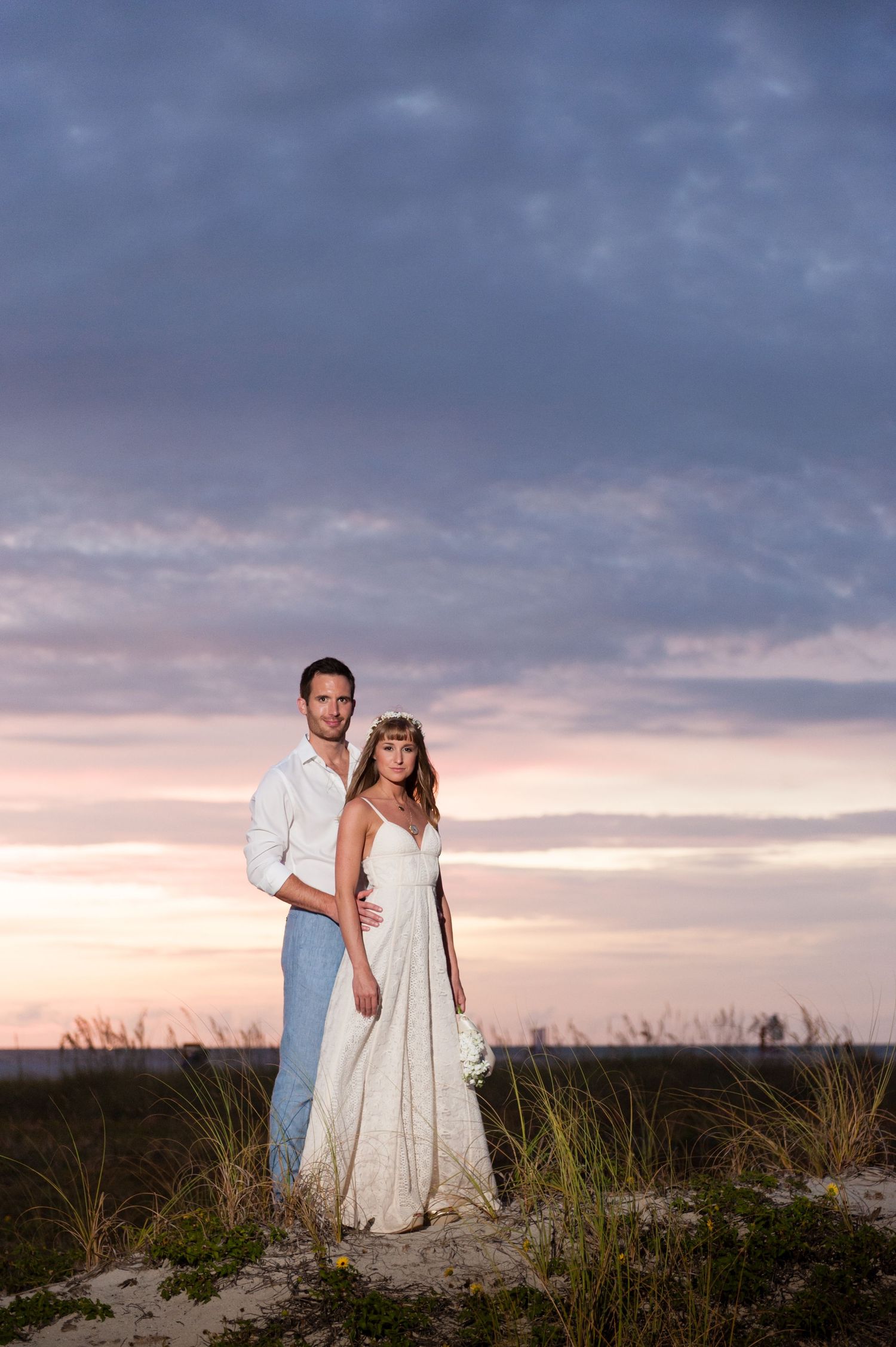Newlywed couple embraces against a stunning purple and pink sunset on the beach on Treasure Island, Florida.
