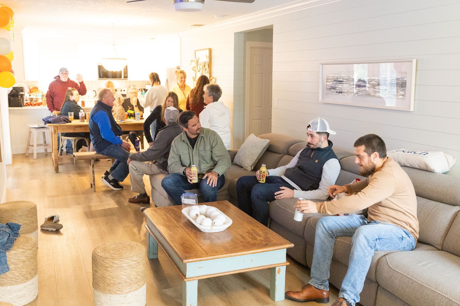 Group of people socializing in a modern living room during a casual gathering.