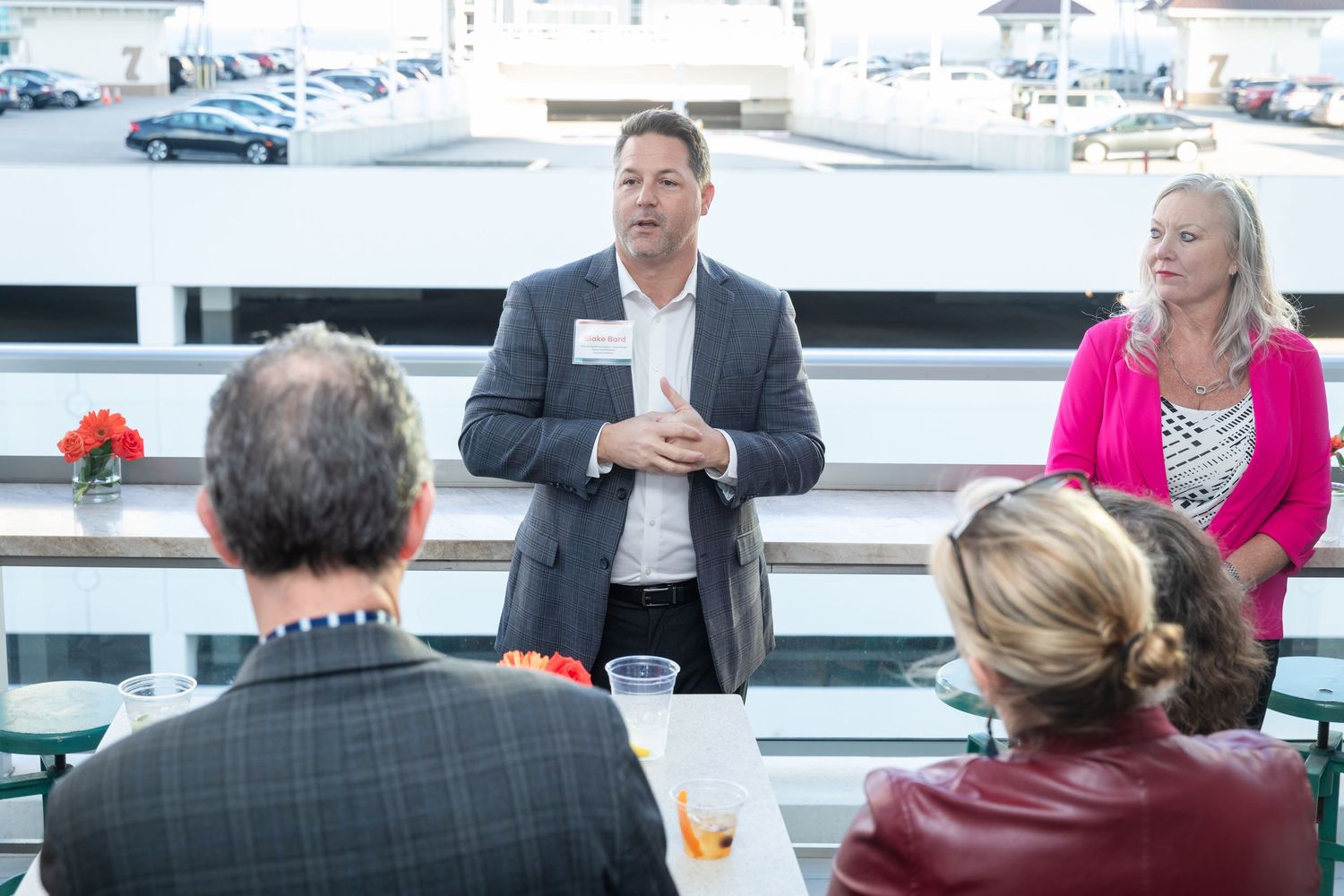 Business professional speaking to a small group at an outdoor networking event on a rooftop.