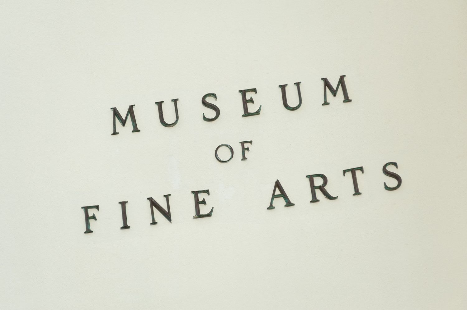 Museum of Fine Arts sign displayed in elegant serif typography on a clean white wall.