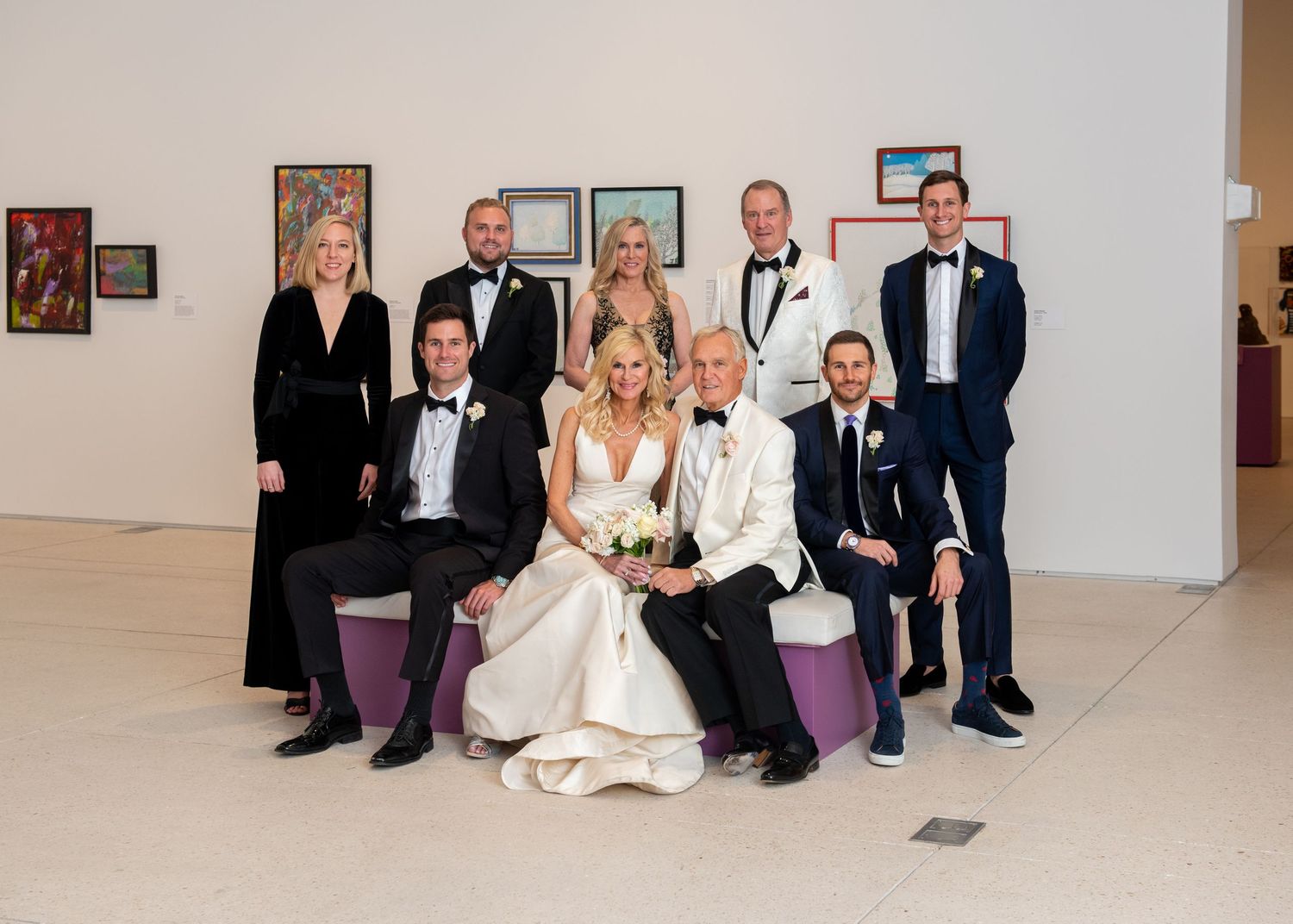 Wedding party group portrait inside art gallery with bride and groom centered among formally dressed guests at Tampa museum of fine art.