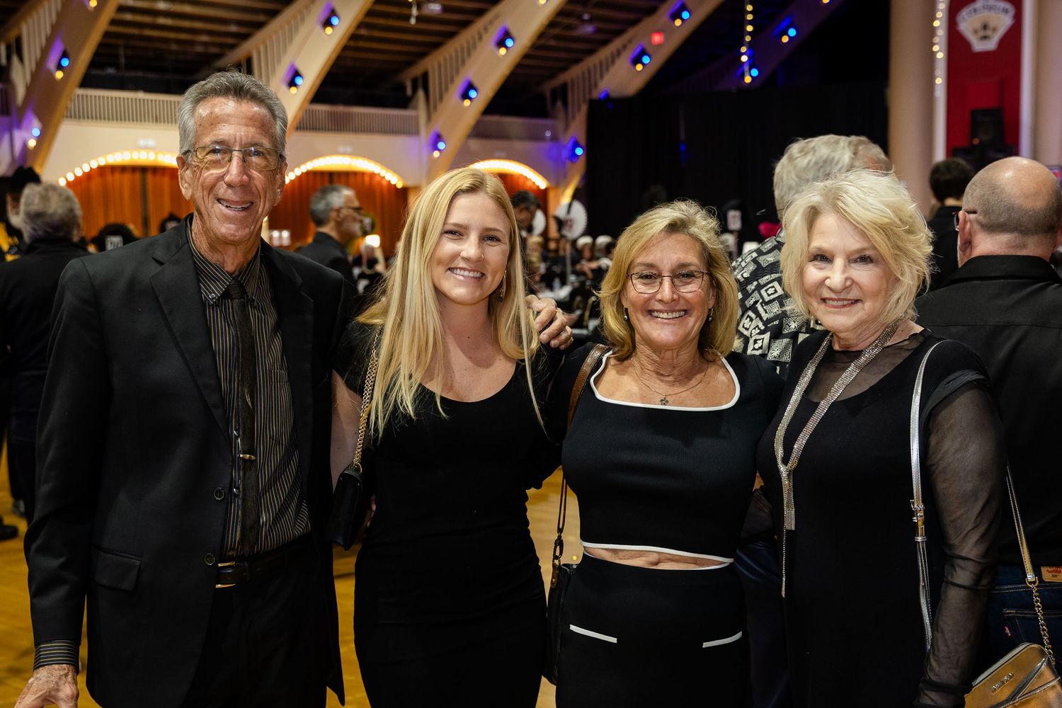 Four elegantly dressed guests pose together smiling at a formal casino night gala event.