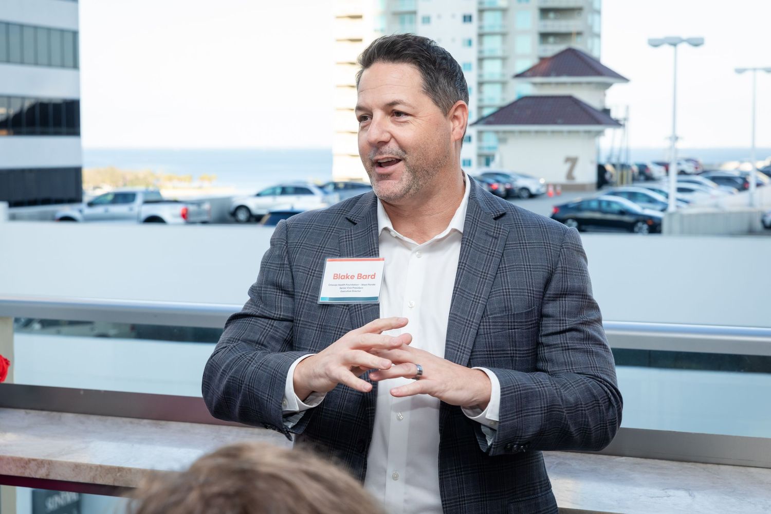 Smiling businessman with name tag networking at an outdoor rooftop business event.