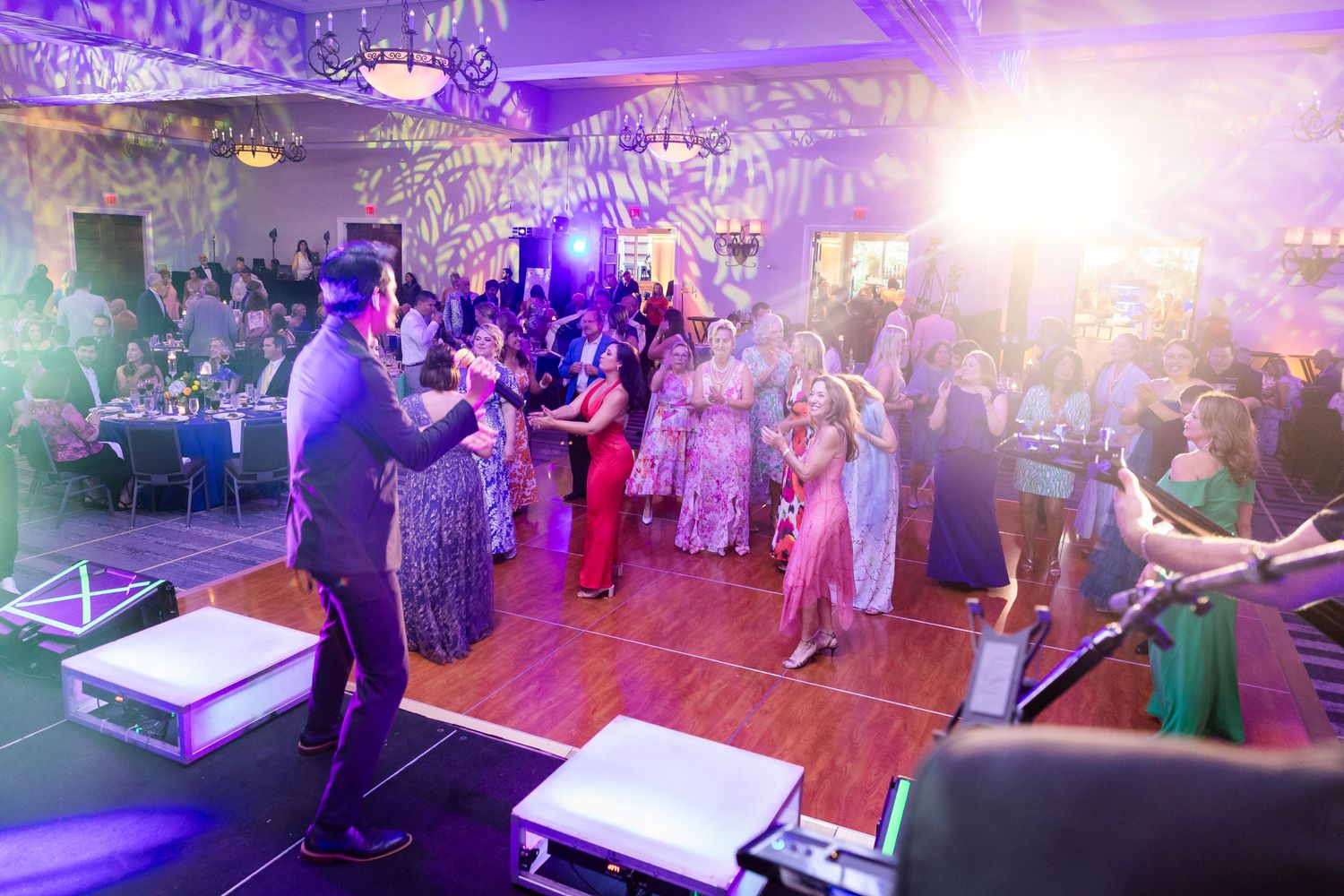 Live band performing on stage at an elegant gala event with guests dancing on a purple-lit dance floor.