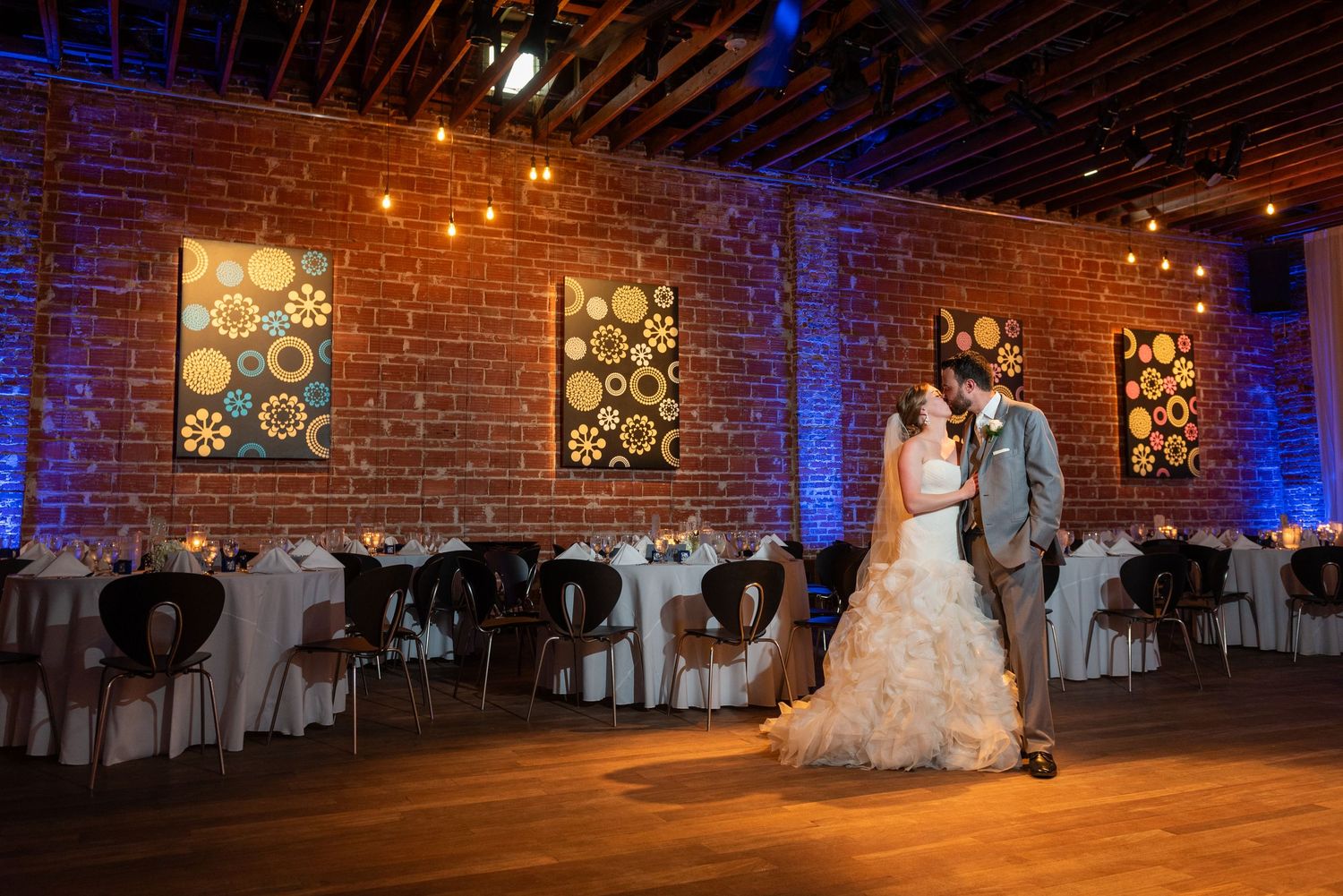 Bride and groom share first dance in elegant brick-walled reception venue.