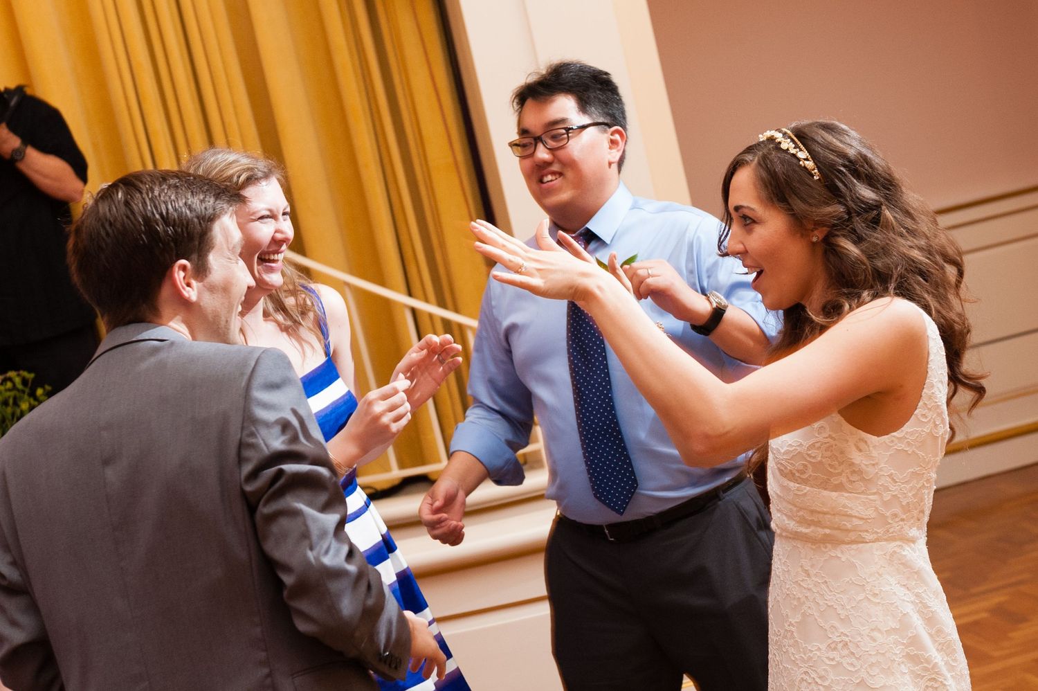 Bride and wedding guests laughing and dancing joyfully together at a lively wedding reception.