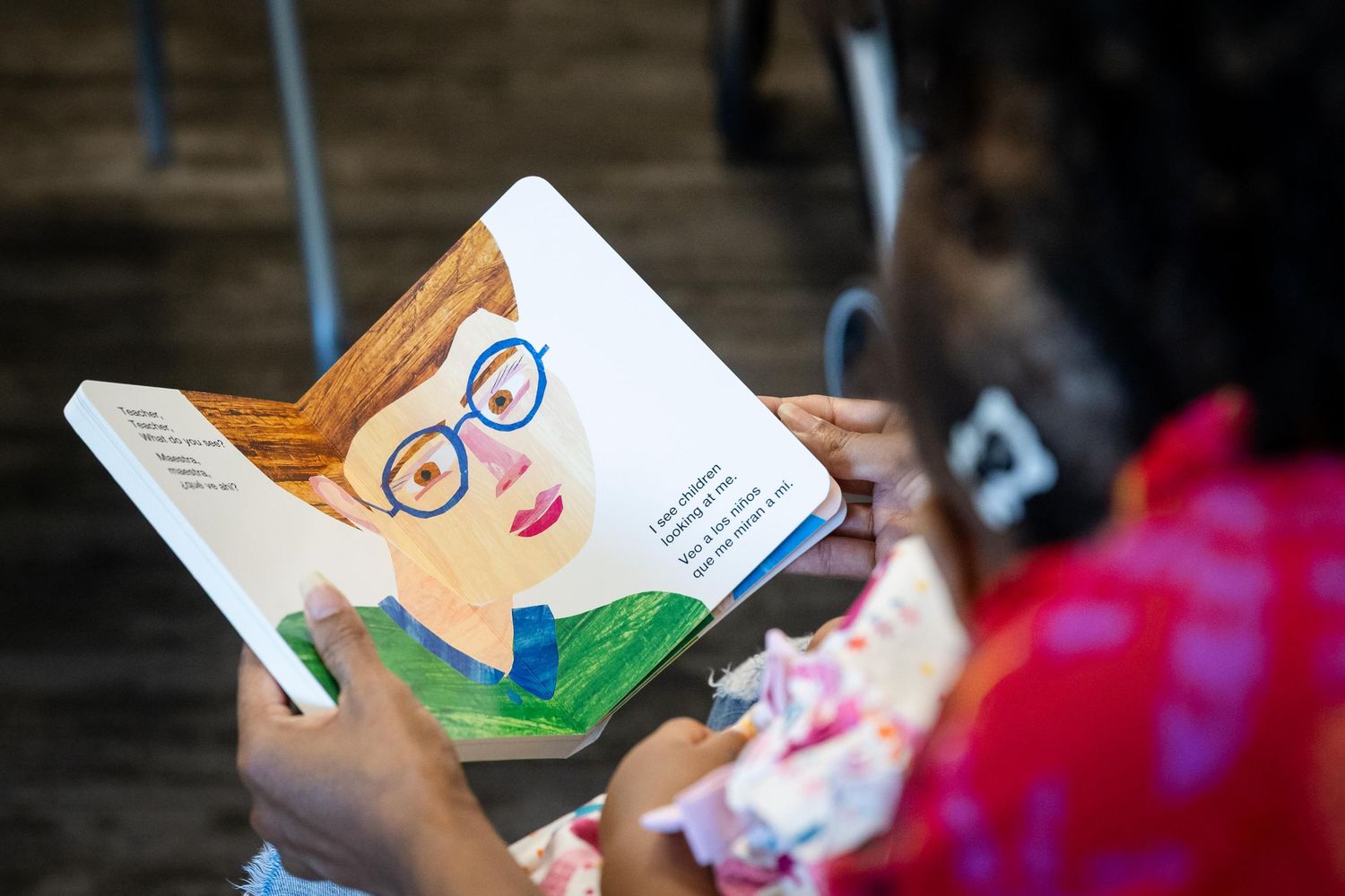 Person holding a colorful illustrated children's book featuring a character with glasses during a reading event.