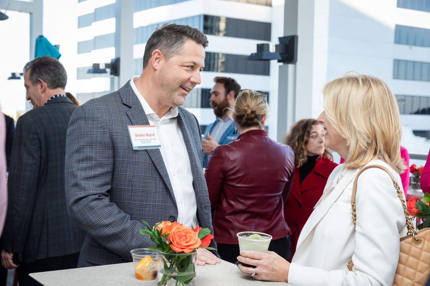 Two business professionals engaged in conversation at a corporate networking event with floral decor.