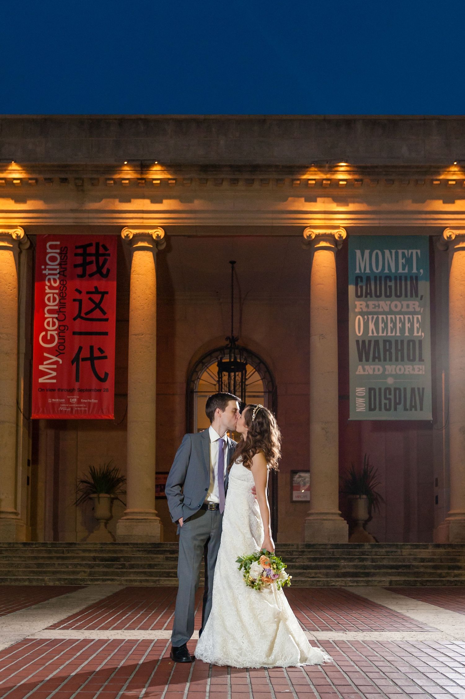 Newlyweds kissing at night outside illuminated museum with Monet and My Generation banners.