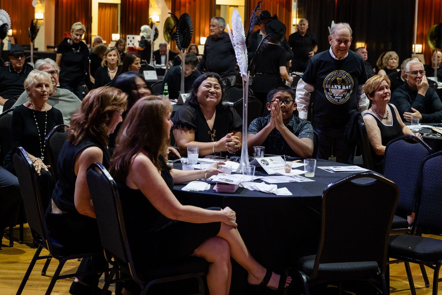Guests laugh and clap at round tables during a festive casino night charity gala event.