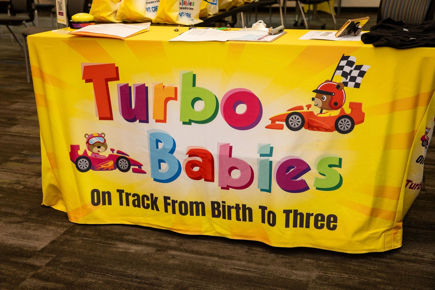 Turbo Babies colorful yellow banner promoting early childhood development program on track from birth to three.