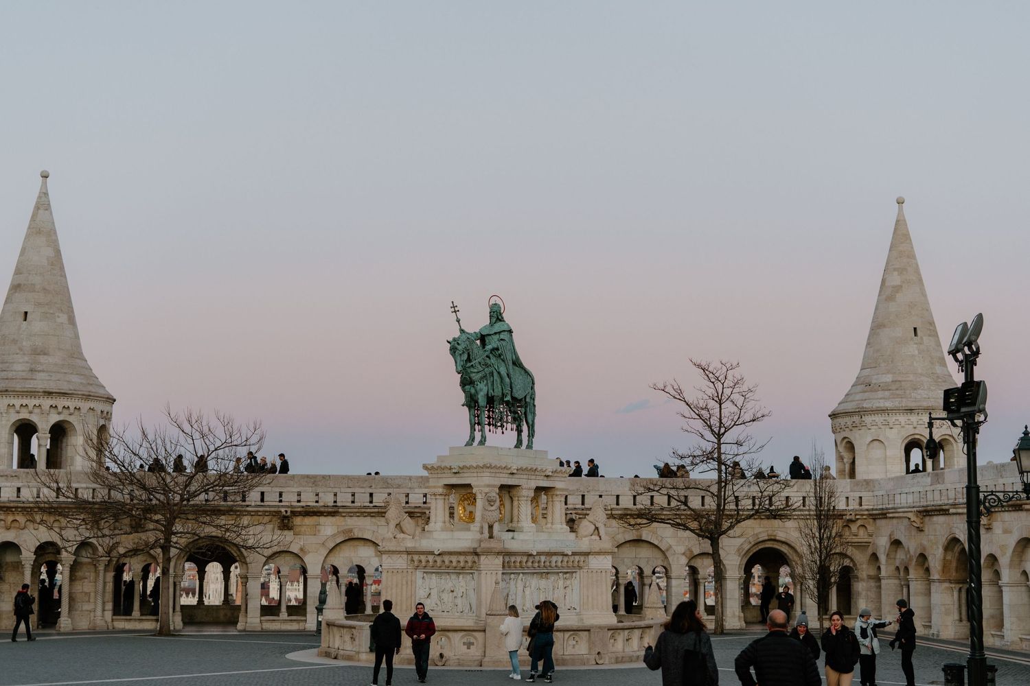 The Fisherman's Bastion in Budapest with its iconic white towers and equestrian statue at twilight.
