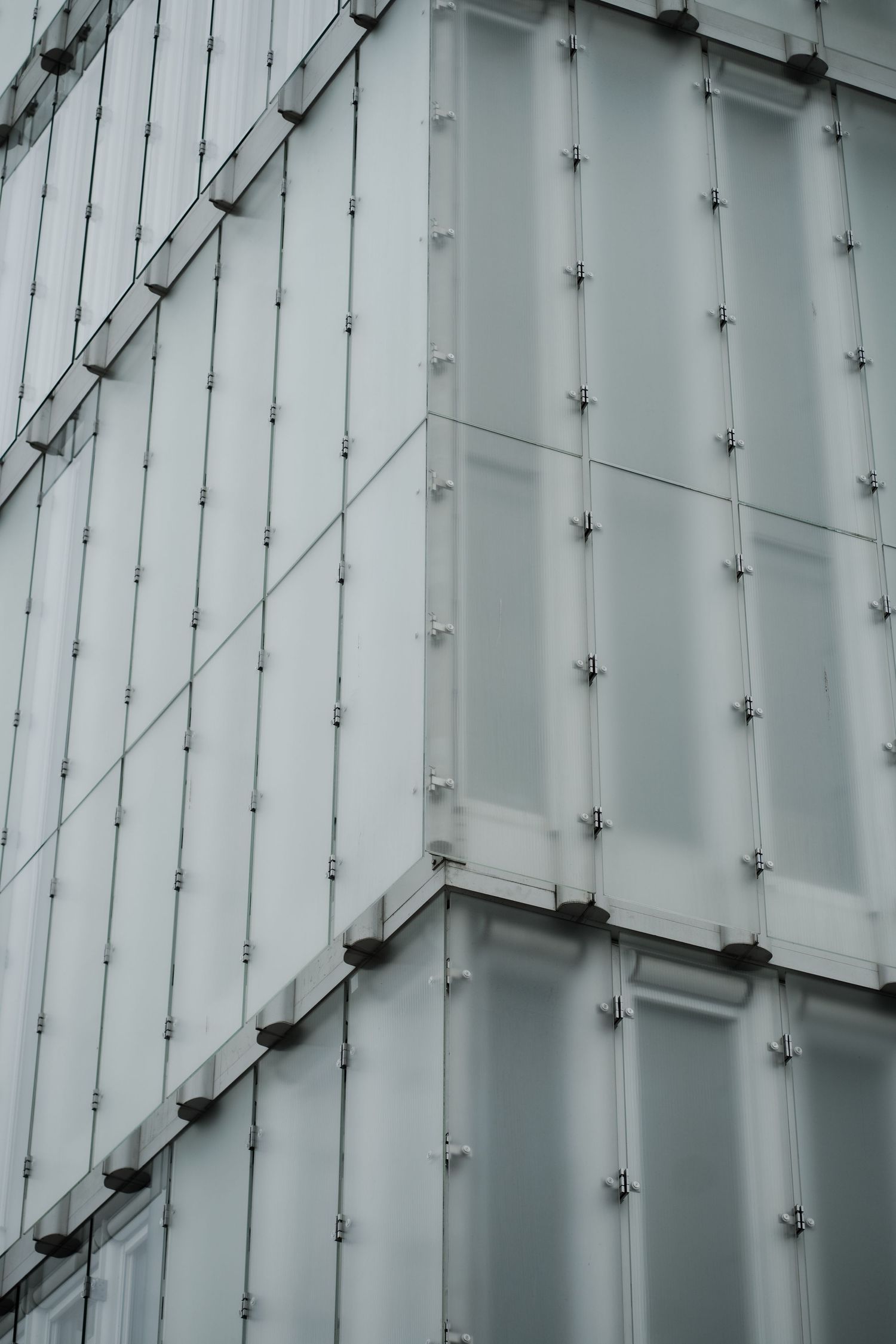 Close-up of white industrial wall panels with geometric bolt pattern and diagonal support beams in modern architecture.