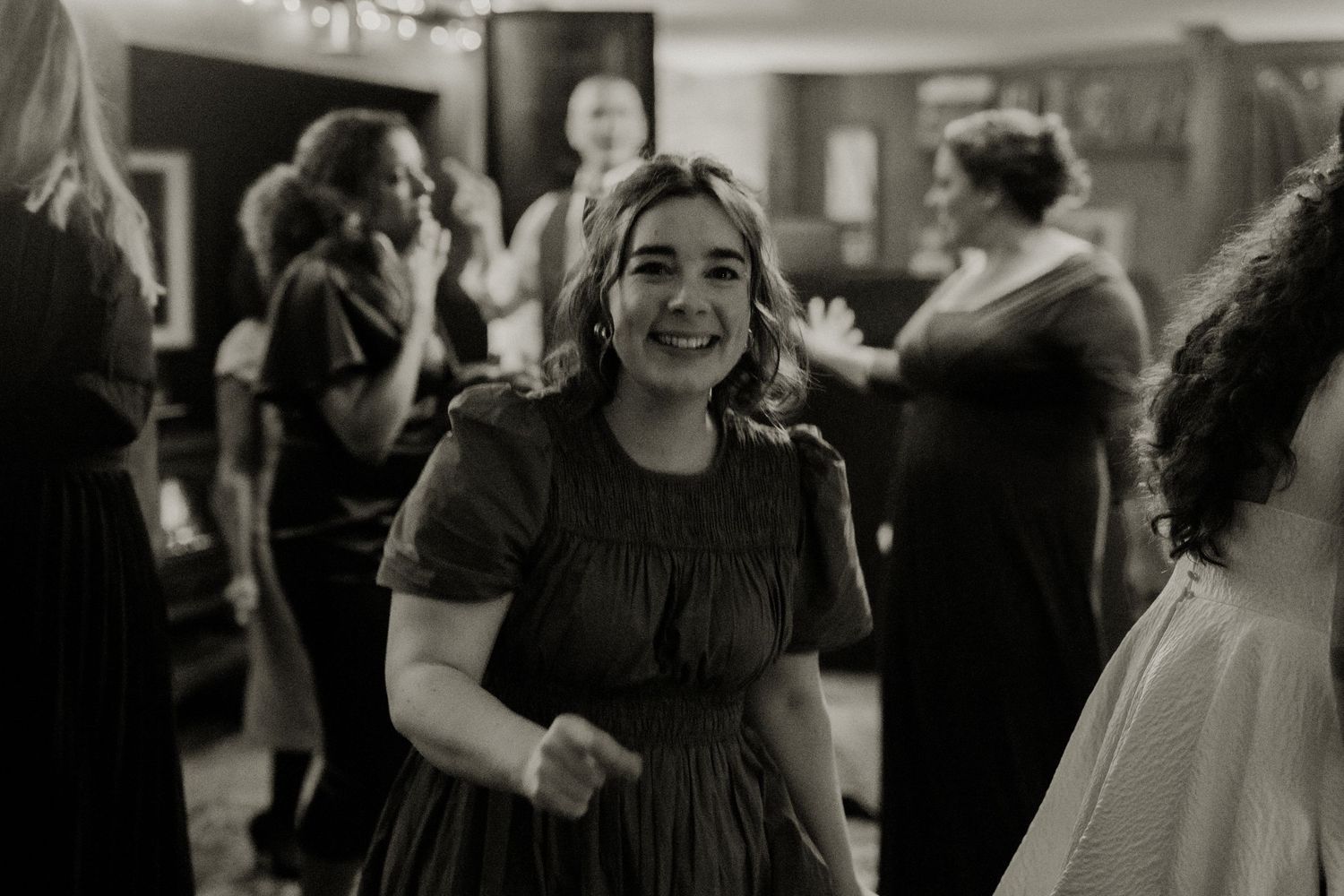 Smiling woman in dark dress enjoying herself on the dance floor at a wedding reception.