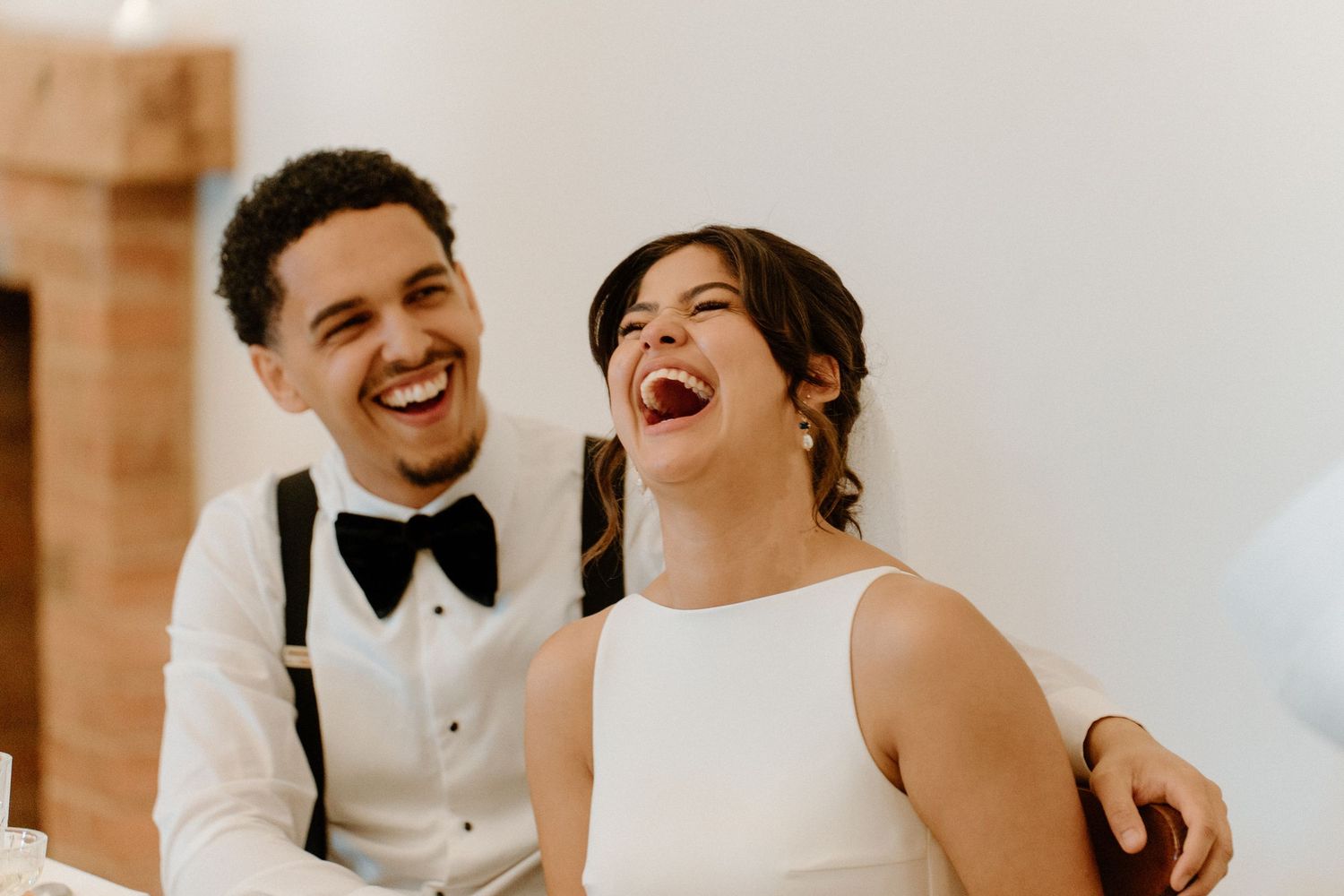 Bride and groom laughing joyfully together during their wedding reception celebration.