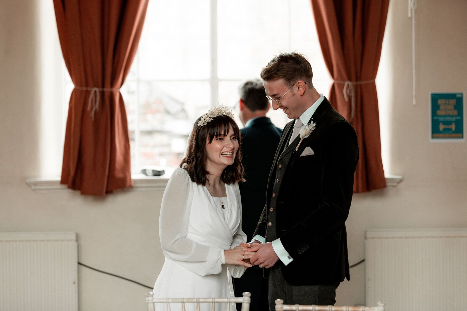 An intimate wedding moment captured by a window with rust-colored curtains.