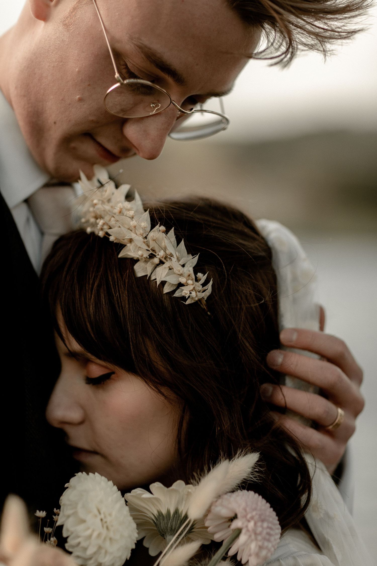A tender close-up wedding portrait highlighting delicate hair accessories and flowers.