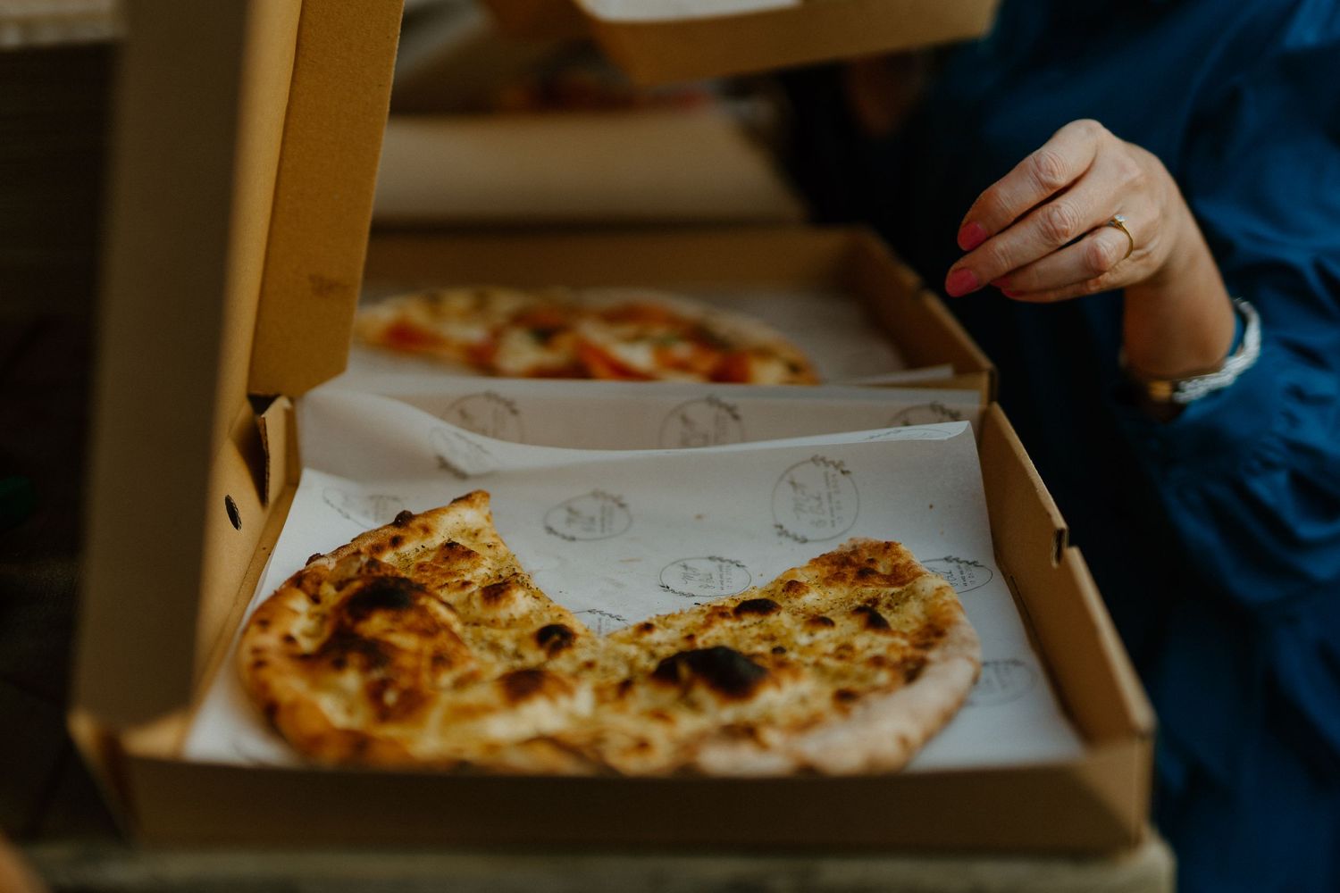 A partially eaten pizza pie sits in an open cardboard delivery box viewed from above.