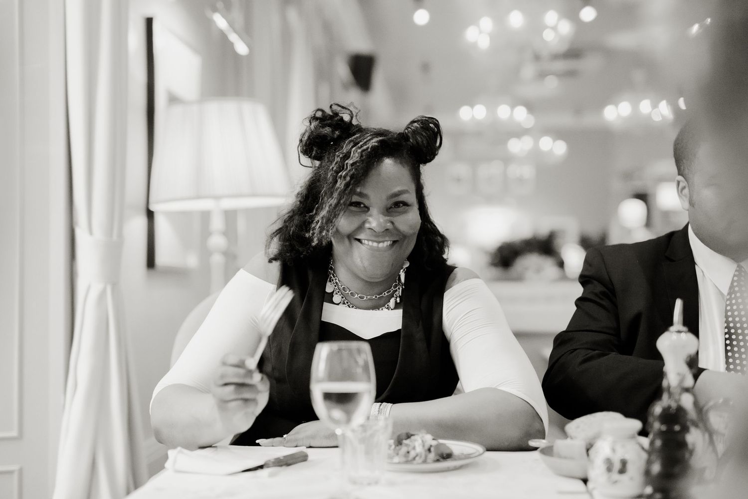 Smiling woman wearing mouse ears seated at an elegant wedding reception table.