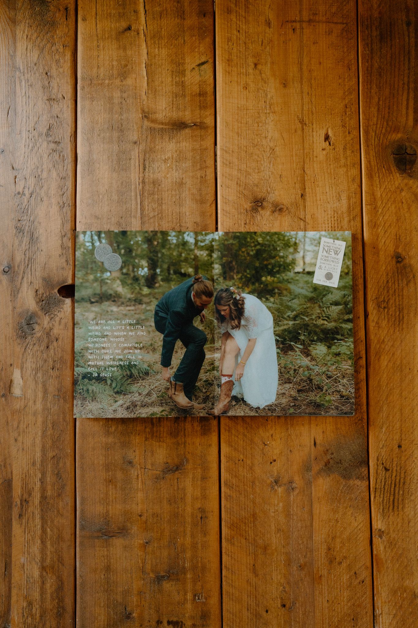 A photograph rests on rustic wooden planks showing a couple in an outdoor forest setting.