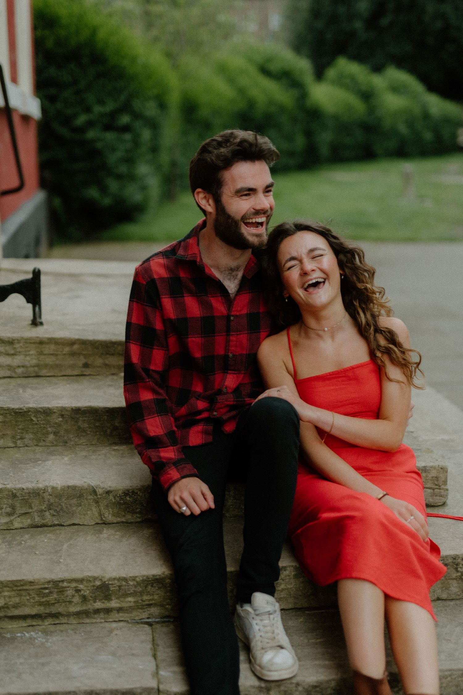 Joyful couple laughing together while sitting on stone steps outdoors.