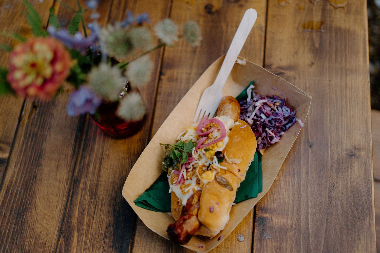 Artfully plated taco on wooden board with colorful garnish and flowers.