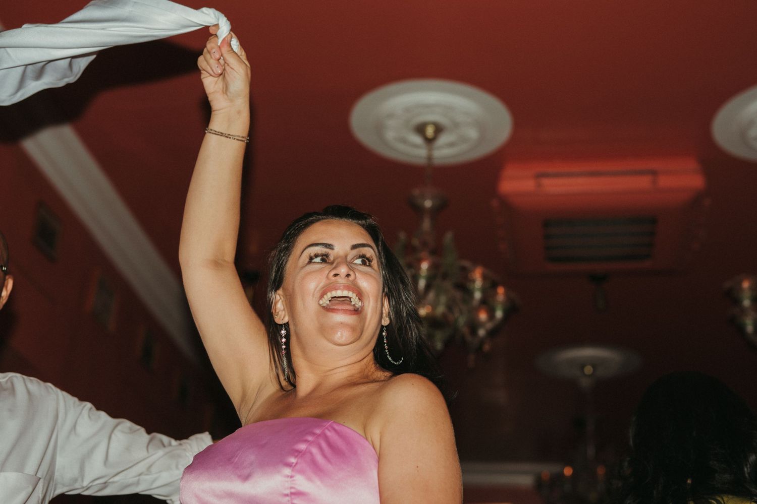 Wedding guest waves their arms while dancing enthusiastically at the reception.