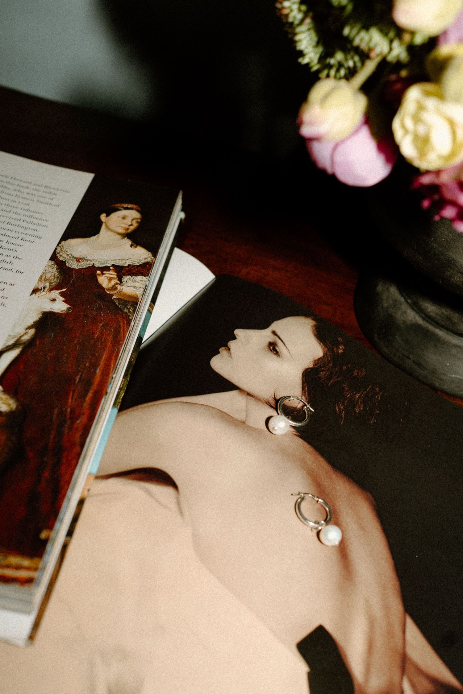 Wedding detail flat lay featuring fashion magazine, pearl earrings, and fresh flowers on a wooden table.