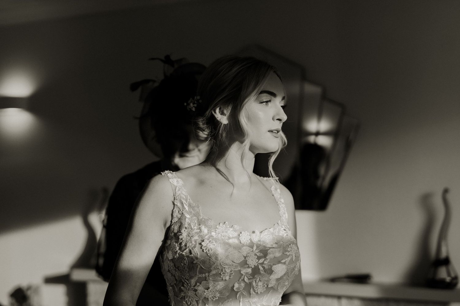 Black and white portrait of bride in lace wedding gown with dramatic lighting and soft shadows.