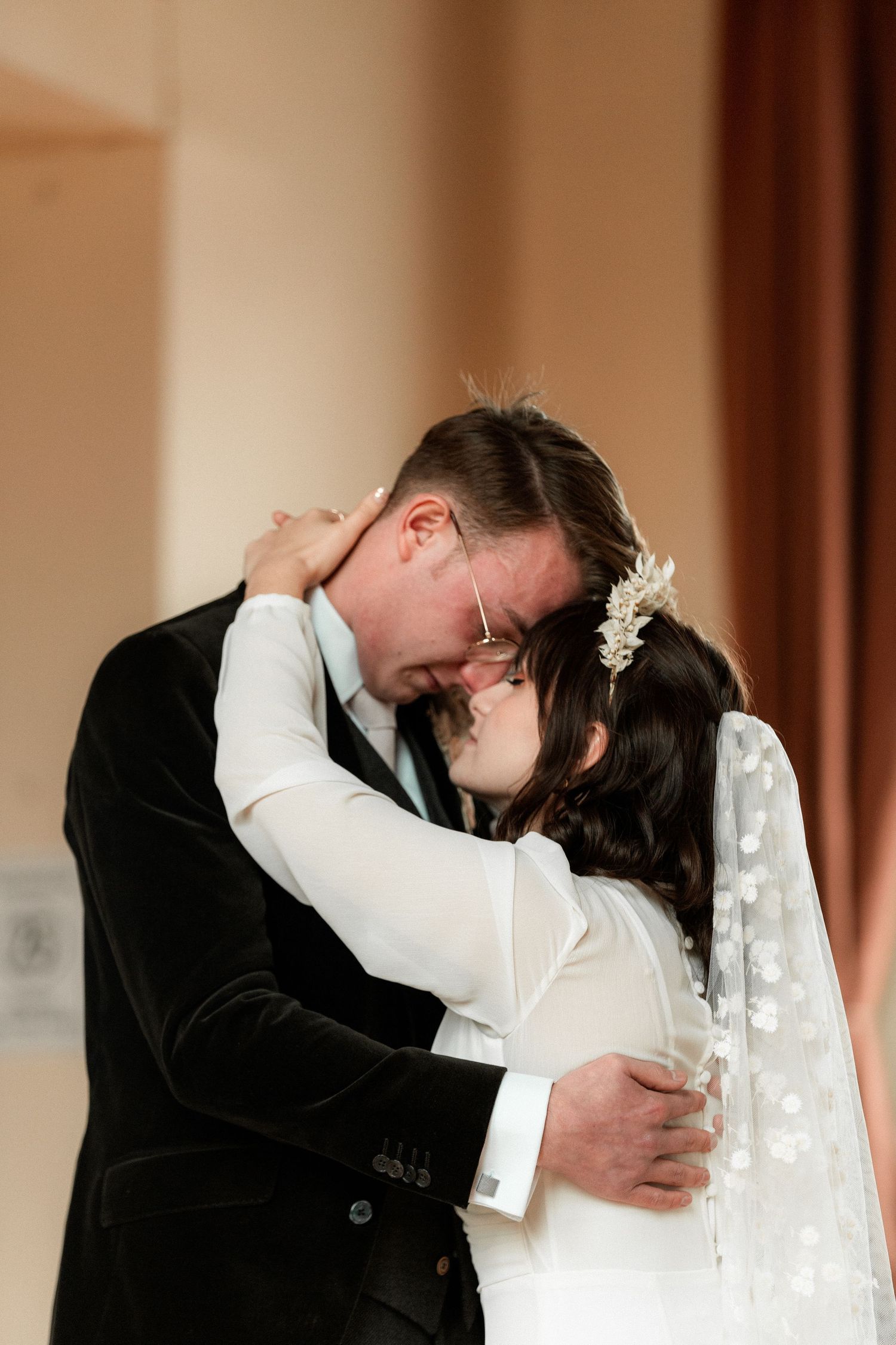 A tender embrace between newlyweds during an intimate wedding ceremony indoors.