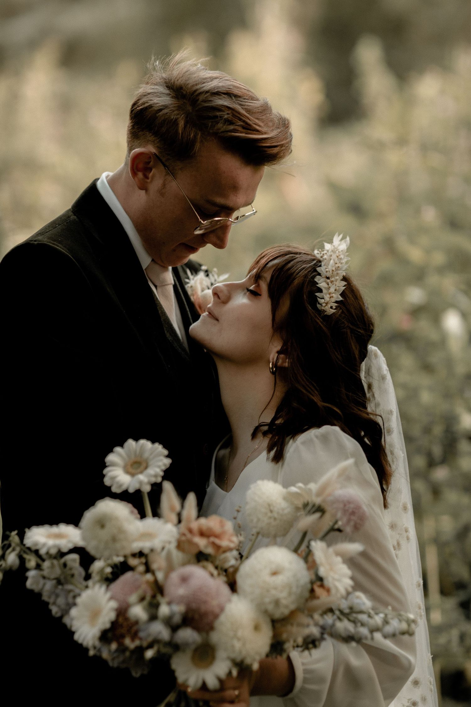 Intimate wedding moment captured with soft lighting and delicate floral bouquet.