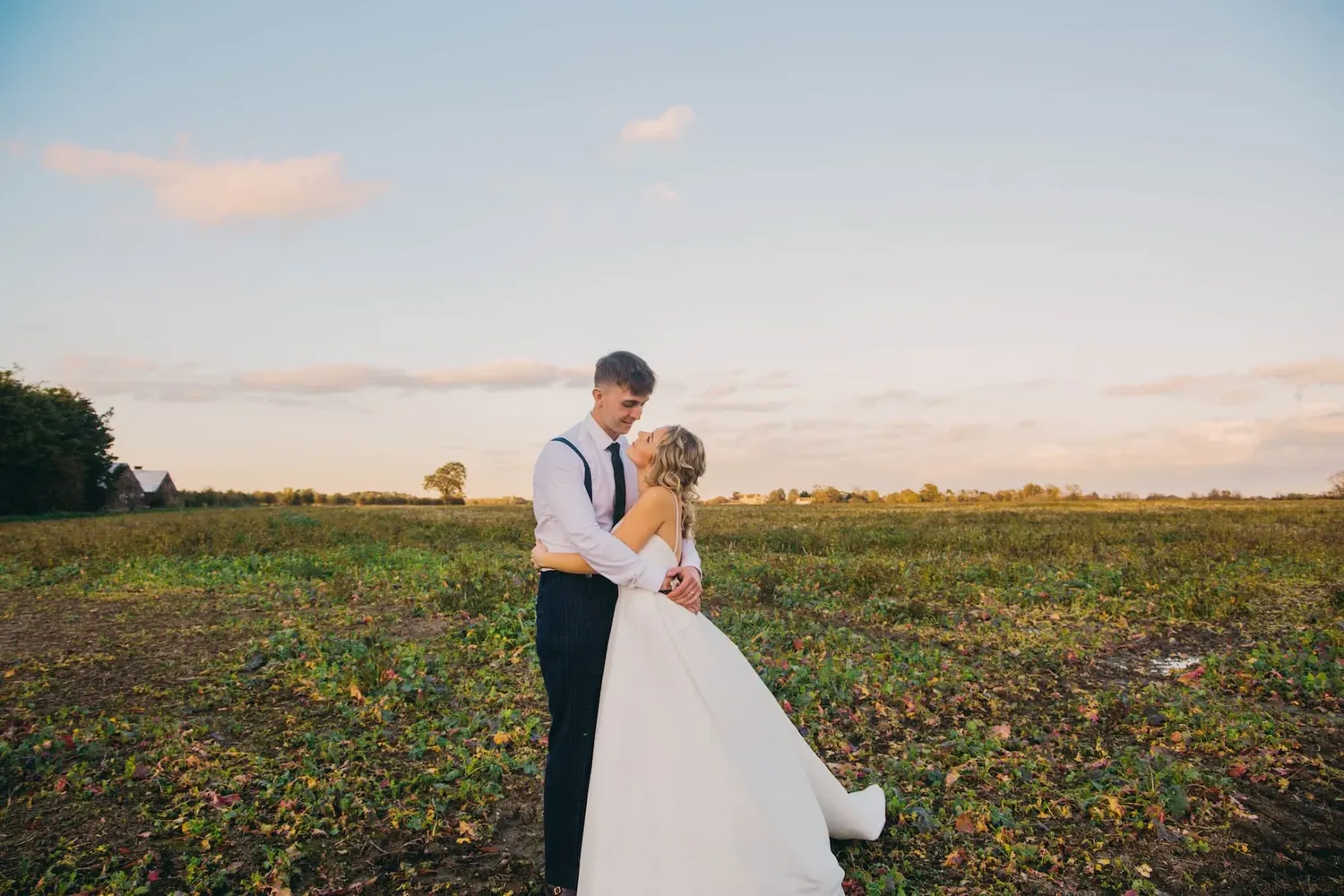 A couple shares a romantic moment in a field at sunset.