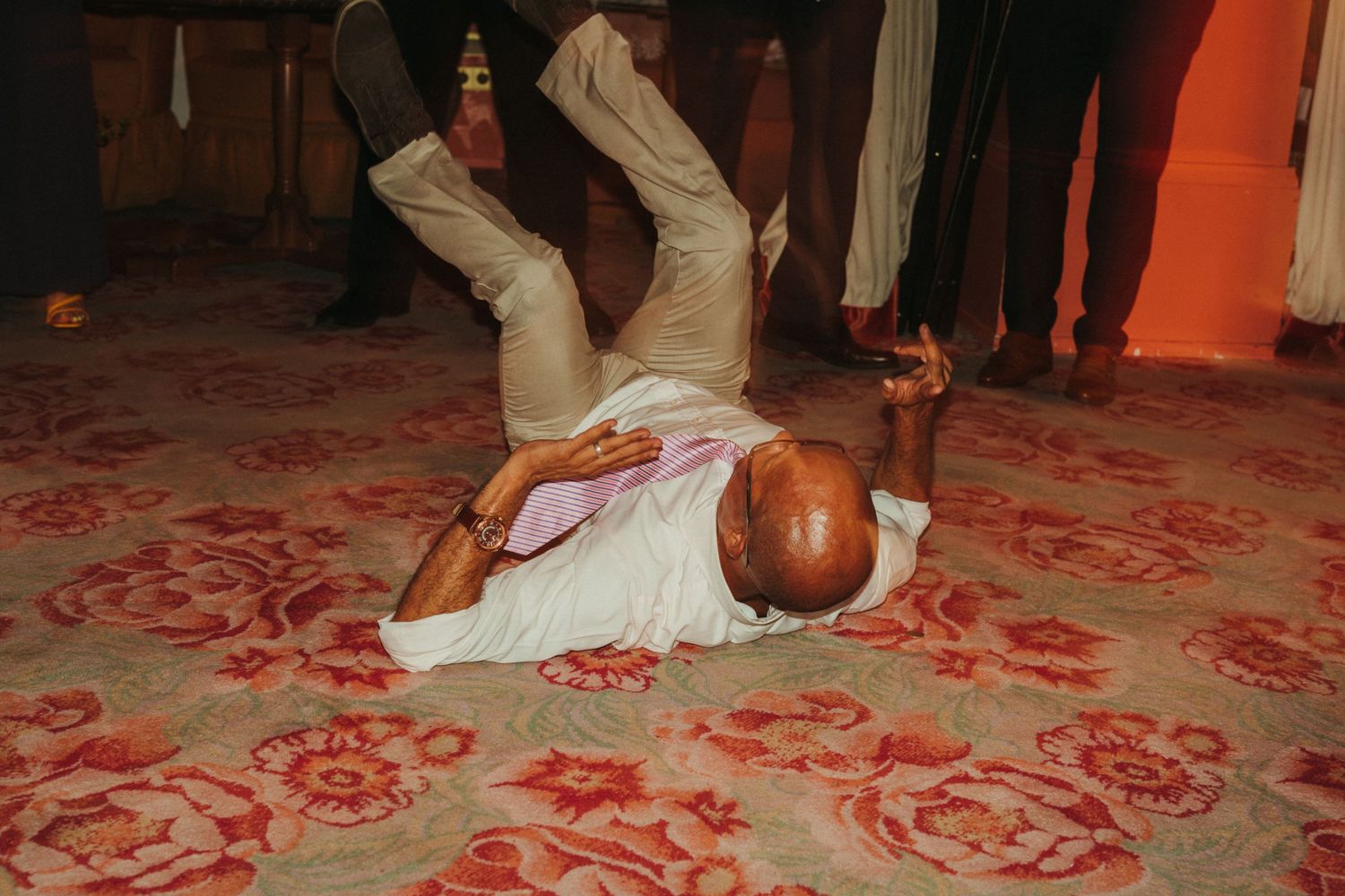 Dancer performs breakdancing move on patterned red carpet during celebration.